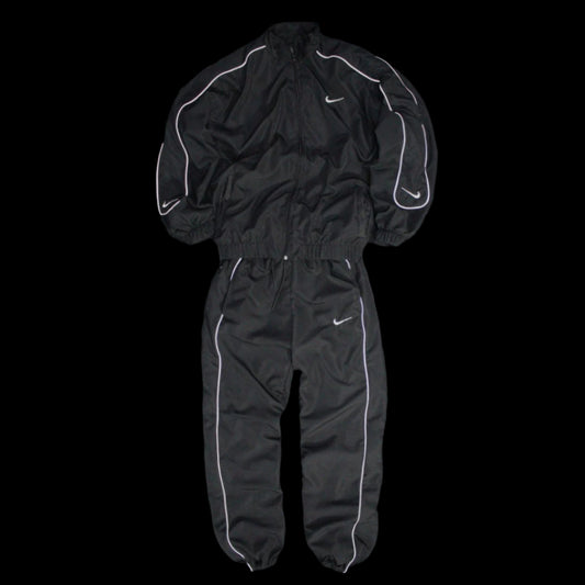  Black Nike tracksuit with reflective piping, featuring a zip-up jacket and matching pants, designed for athletic performance and casual streetwear.